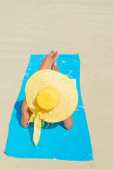 Woman in bikini wearing a yellow hat at tropical beach