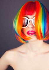 Naklejka premium beautiful woman wearing colorful wig and white sunglasses