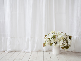 Window design. White curtains, vase with flowers on the wooden f