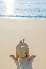 Fototapeta na wymiar Woman with hat laying on the beach