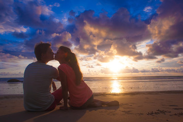 sunset silhouette of young couple in love hugging at beach