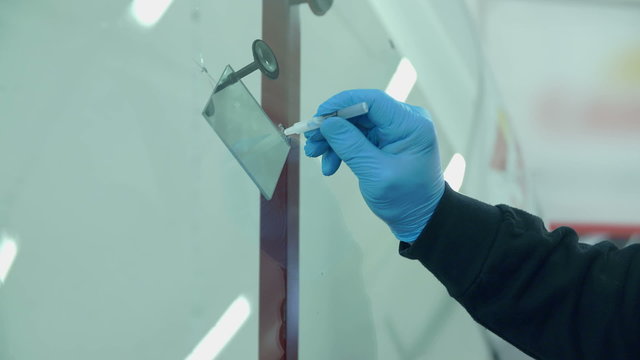 Gluing something on a window in a car repair shop