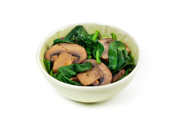 Sauteed Mushrooms and Spinach on White. Selective focus.