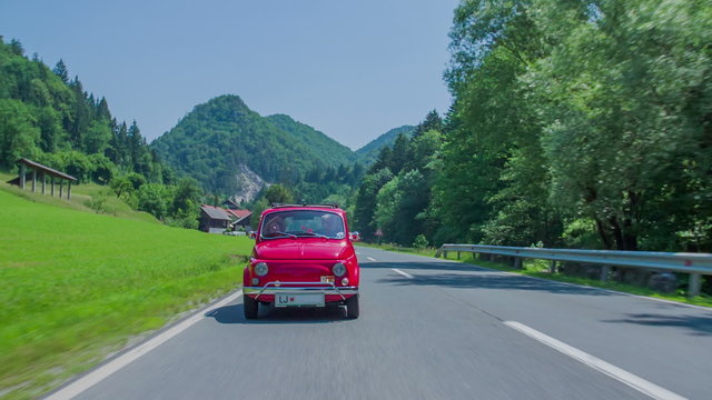 Small red car driving on a country road