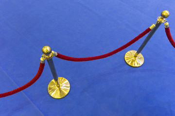 Red velvet rope and a blue carpet. Abstract background
