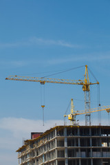 Crane and building construction site against blue sky