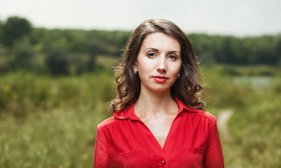 beautiful young girl in red blouse on a background of green natu