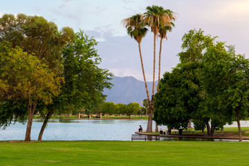 A person fishes at the edge of Alvord Lake in Ceasar Chavez park; Phoenix, Arizona.