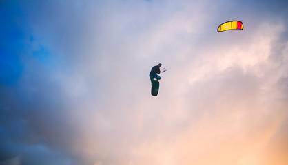 Obraz na płótnie Canvas Kiteboarder performing a jump against sky at sunset