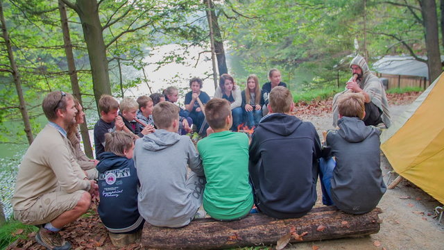 Grop of children with couple listening to the sound of a didgeridoo