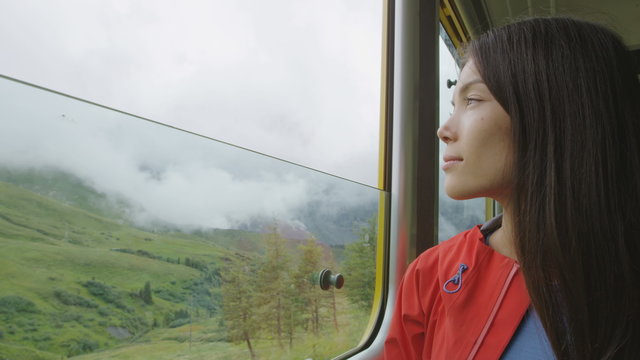 Train Passenger traveling in looking out window seeing Swiss Alps landscape Lauterbrunnen taking train to Jungfraujoch in Switzerland. Happy woman tourist traveling in summer.