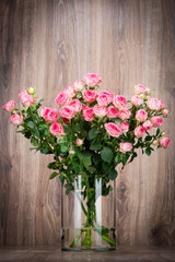 Bouquet of roses in the vase on wooden background