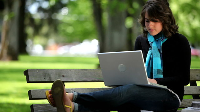College student sitting on bench with laptop