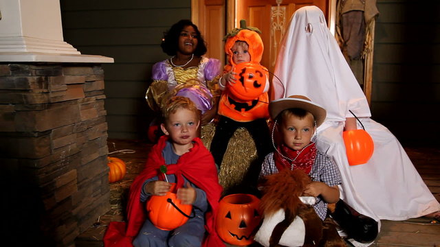Children sitting on porch in Halloween costumes