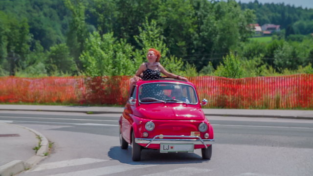 Small red vintage car arrives into town