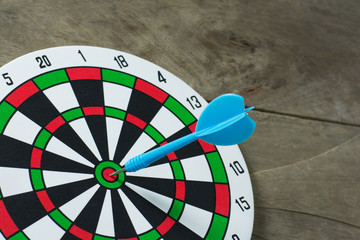 Blue darts arrows in the target center on wooden background. Suc