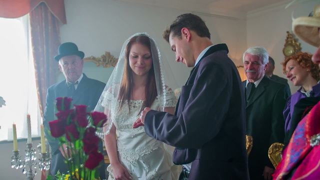 A young couple is exchanging the rings at their wedding and kissing each other