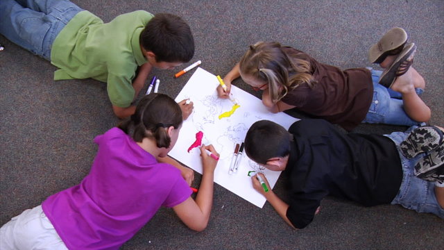 Four kids laying on floor coloring picture
