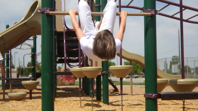 Girl hanging upside down on play equipment