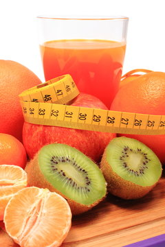 Fresh fruits, tape measure and glass of juice