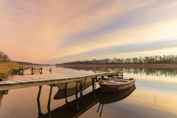 Fototapeta na wymiar Łódka przy drewnianym pomoście nad jeziorem