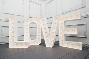 Custom made L O V E letters with light bulb in the corner of vintage room