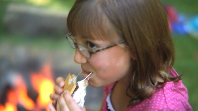 Girl eating a smore by campfire