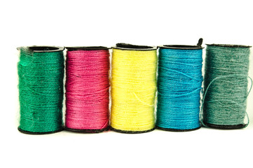 still life of spools of thread on a wooden background / Spool of thread isolated on white / three different spools of thread on white background / Sewing threads multicolored background closeup