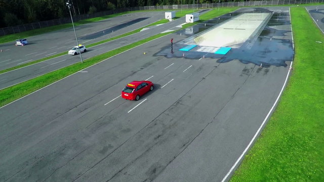 Red sports car is driving on a slippery track with water fountains