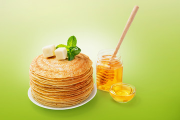 Stack of fresh baked pancakes with butter, honey and hot tea.