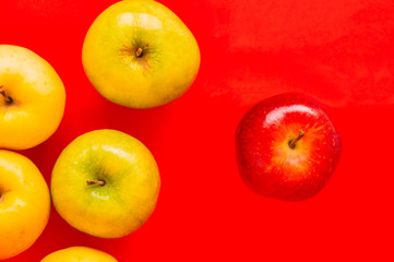 One red apple standing out from a group of other apple on a red