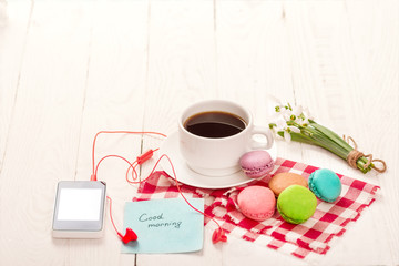 Coffee, macaroons and cream with a good morning card on a white table