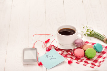Coffee, macaroons and cream with a good morning card on a white table