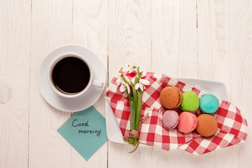 Beautiful delicious almond on a plate with snowdrops and a cup of coffee on a wooden table