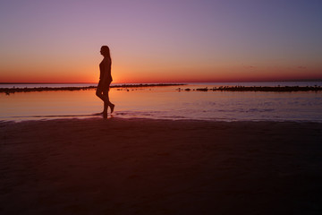 Fototapeta premium teenage girl walking in water on beach in sunset, vintage toned