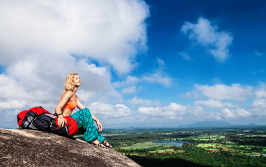 Naklejka premium Young woman backpacker on the top of mountain Pidurangala, Sri-Lanka