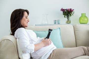 Pregnant woman holding headphone on belly 