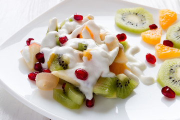 fruit salad with ice cream on a white plate decorated with berries pomegranate