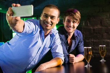 Two men taking a selfie on phone at bar counter