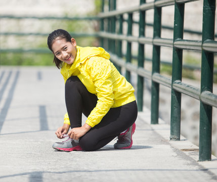 Young asian woman exercising outdoor in yellow neon jacket, tyin