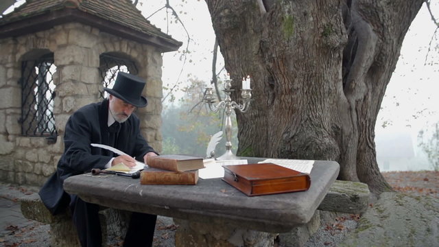 Writing a poem at a stone table in front of big tree 