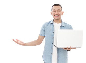 handsome young man holding a laptop while presenting copy space