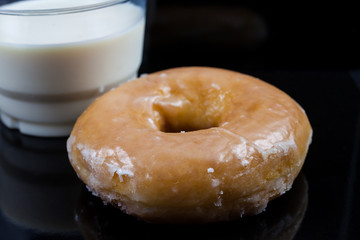 Donuts and milk for breakfast on black background.