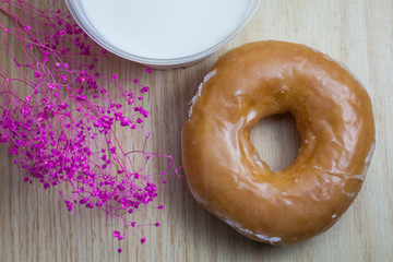 Donuts and milk for breakfast on wooden background.