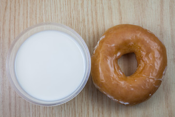 Donuts and milk for breakfast on wooden background.