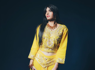 Fototapeta premium Vintage Bollywood fashion girl in yellow clothes against dark bl