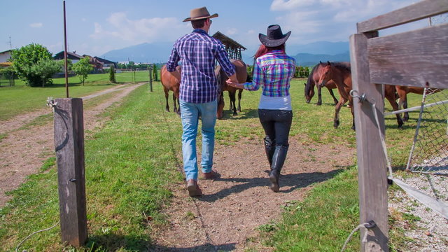Lovely young couple is walking into the riding stables