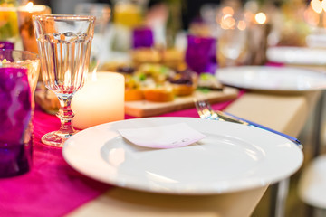 Decorated table ready for dinner. Beautifully decorated table set with flowers, candles, plates and serviettes for wedding or another event in the restaurant.