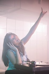 Pretty female DJ waving her hand while listening 