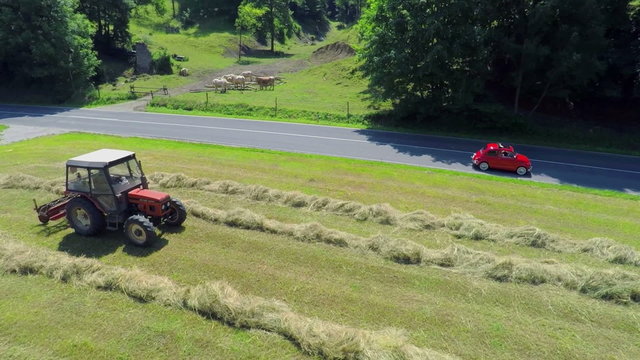 Red retro zastava passes a tractor when it is hay harvesting